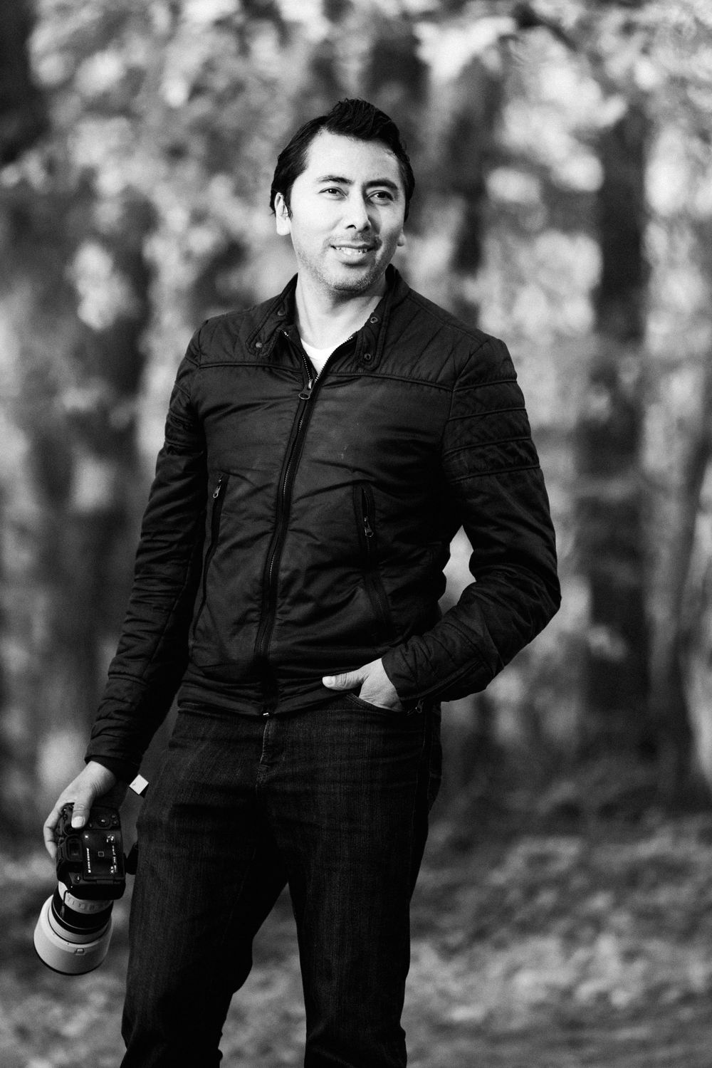 Javier Quiroga holding his camera outdoors, photographed in black and white.
